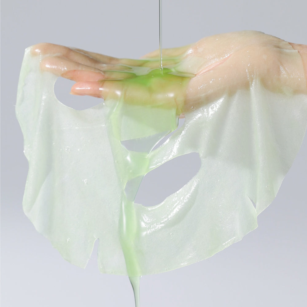 CELIMAX Glowy Skin Noni Ampoule Mask sheet draped over a hand with pale-green essence.