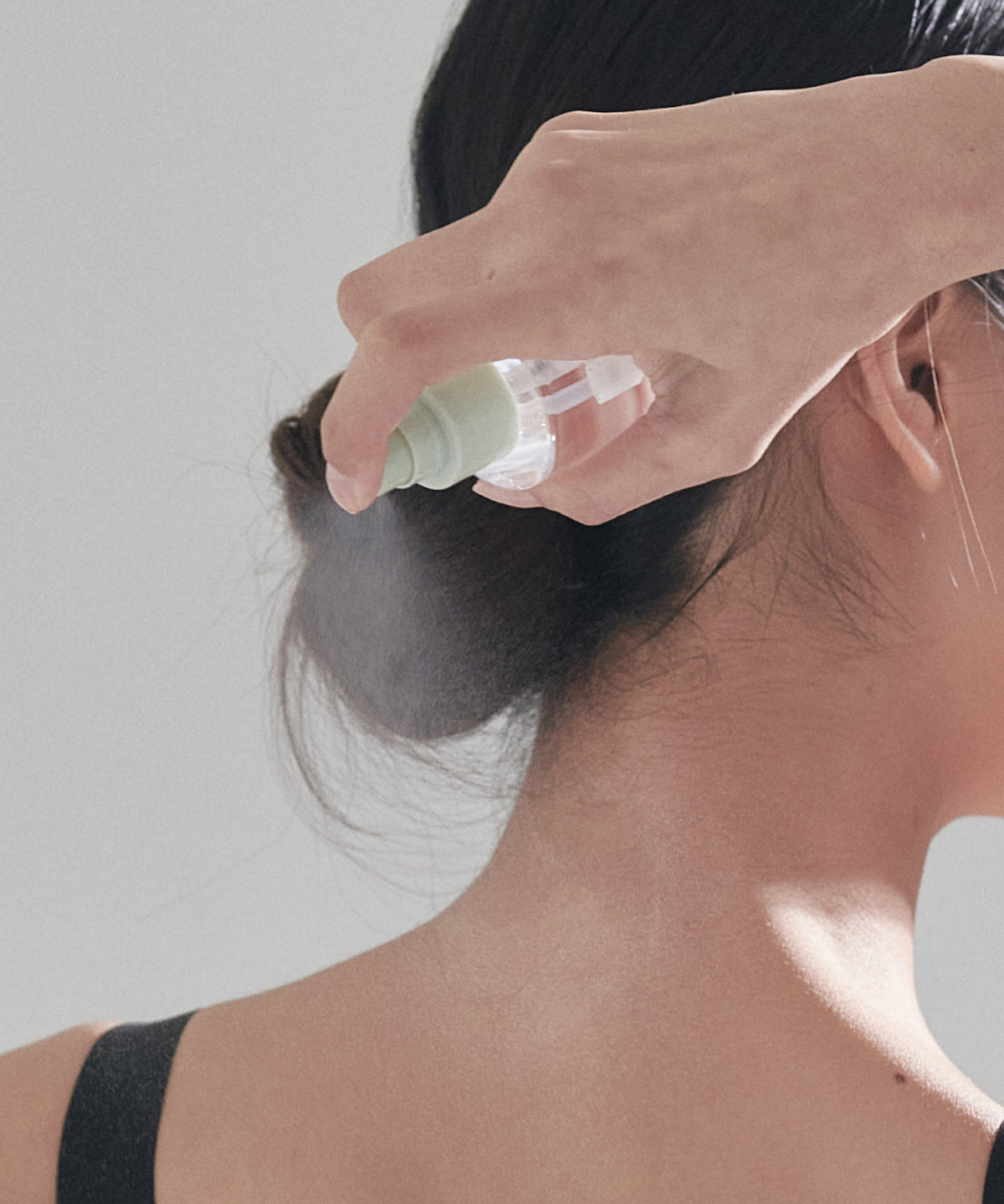 CELIMAX Heartleaf BHA Body Mist bottle held upside down, spraying mist toward the back of the neck