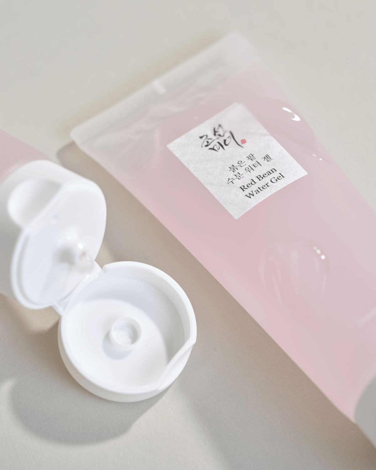 Primer plano de la etiqueta del tubo de Beauty of Joseon Red Bean Water Gel de 100 ml y su tapa abatible blanca