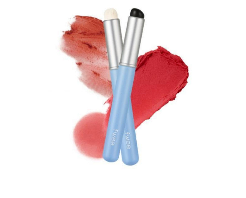 Two blue-handled FWEE Fingerlike Lip Brush tools with pale bristles and a black rounded tip beside red swatches
