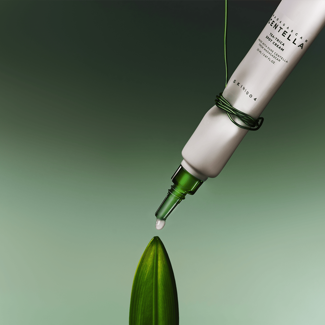 Tubo de SKIN1004 Tea-Trica Spot Cream con la boquilla verde descubierta y una gota blanca en la punta
