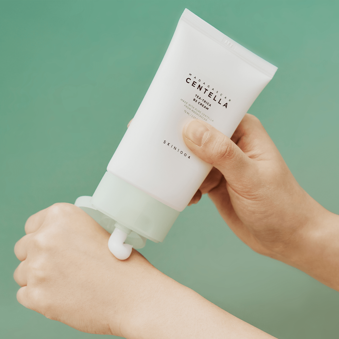 SKIN1004 Tea-Trica B5 Cream tube dispensing white cream onto the back of a hand